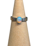 Ring with a colorful gemstone on a beige cone stand