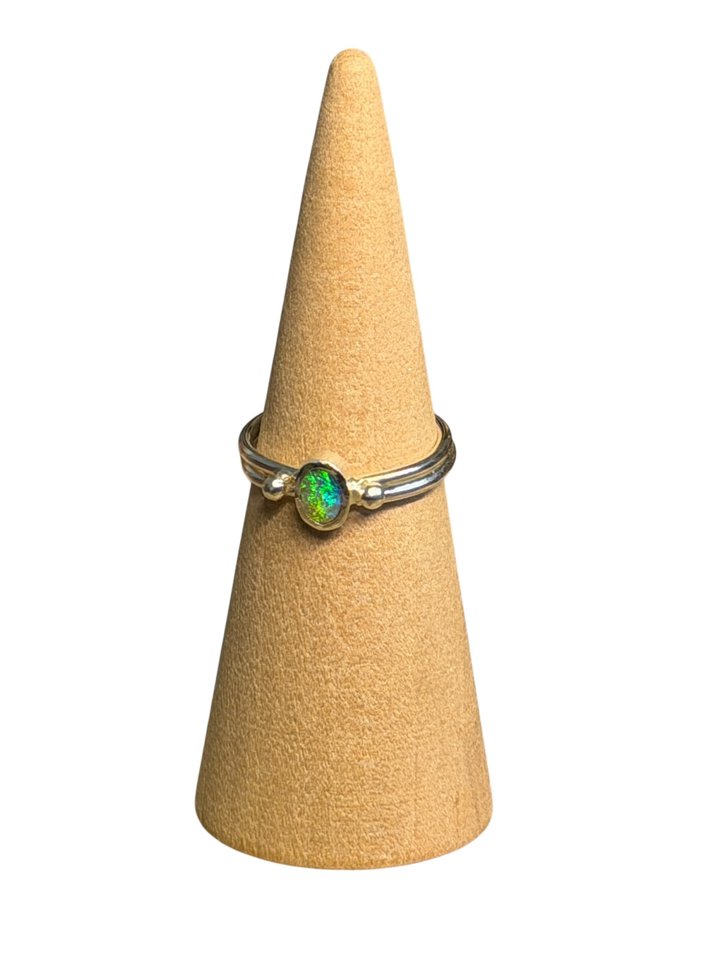 Ring with a green gemstone on a beige cone-shaped stand against a white background