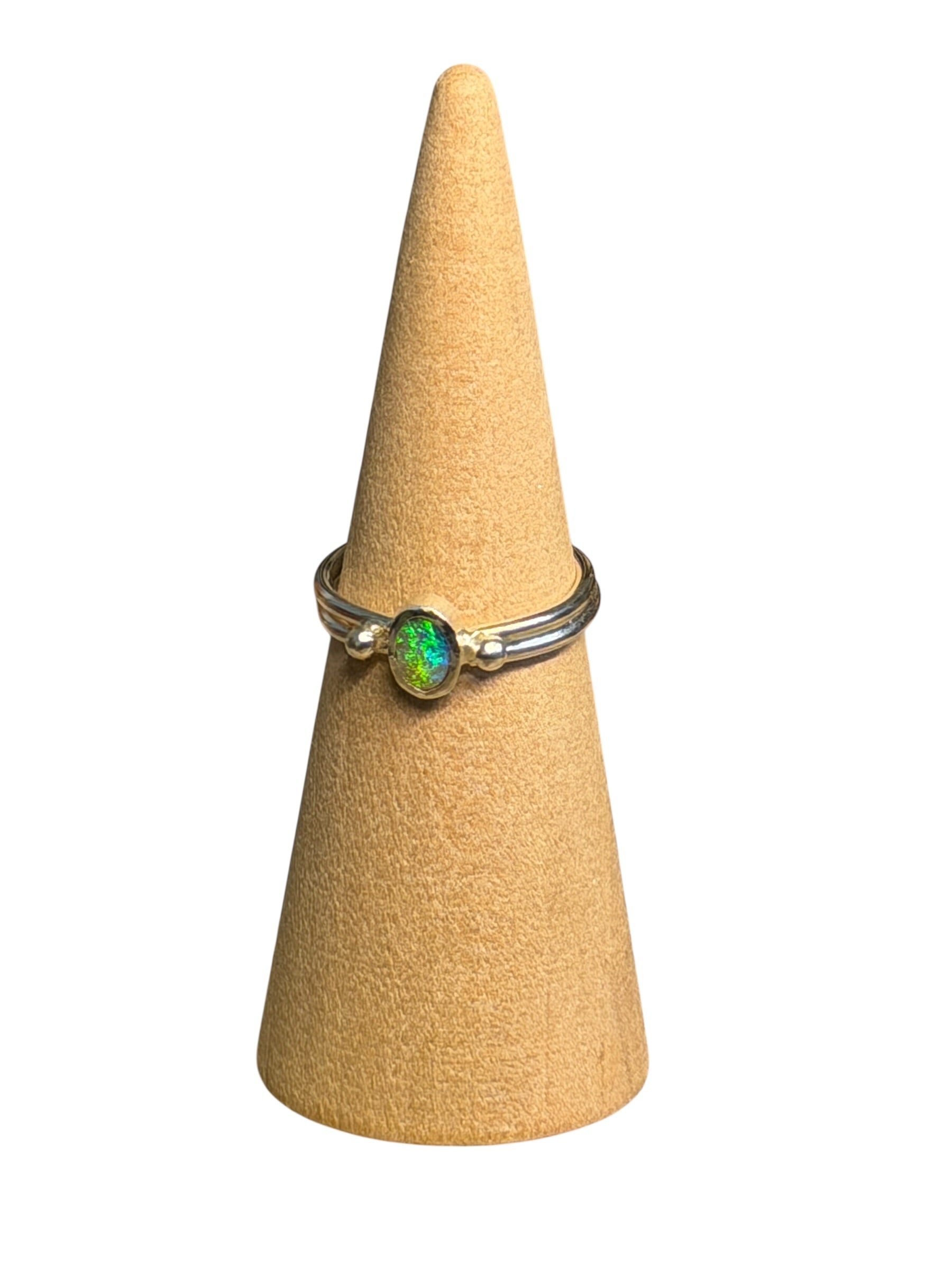 Ring with a green gemstone on a beige cone-shaped stand against a white background