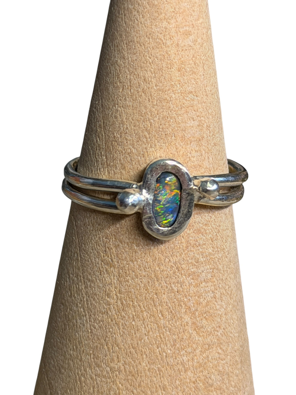 Silver ring with an opal stone on a wooden stand