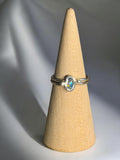 Silver ring with a gemstone on a beige cone-shaped jewelry display