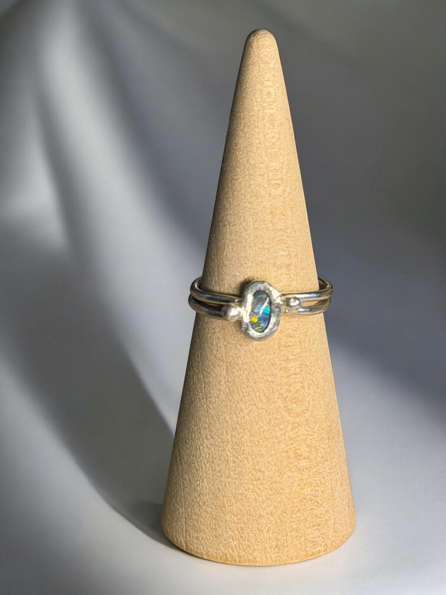 Silver ring with a gemstone on a beige cone-shaped jewelry display